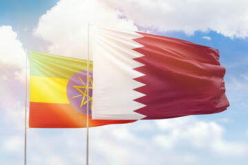 Sunny blue sky and flags of qatar and ethiopia