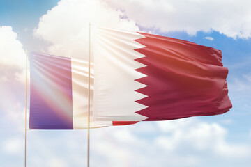 Sunny blue sky and flags of qatar and france