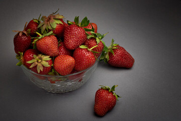strawberries in a bowl. strawberries in a glass plate on a gray background