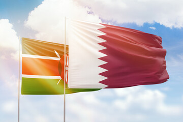 Sunny blue sky and flags of qatar and kenya