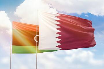 Sunny blue sky and flags of qatar and libya
