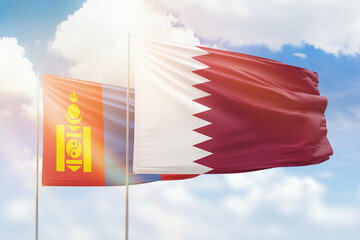 Sunny blue sky and flags of qatar and mongolia