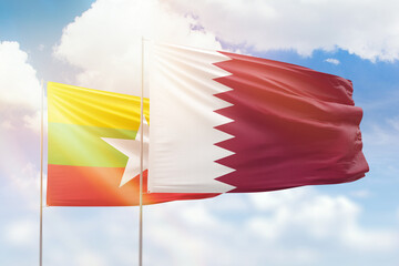 Sunny blue sky and flags of qatar and myanmar