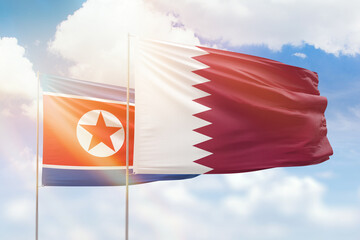 Sunny blue sky and flags of qatar and north korea