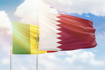 Sunny blue sky and flags of qatar and senegal