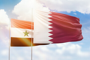 Sunny blue sky and flags of qatar and syria