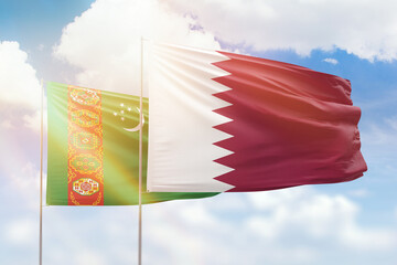 Sunny blue sky and flags of qatar and turkmenistan