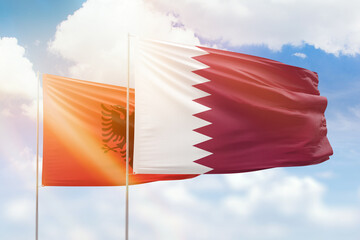 Sunny blue sky and flags of qatar and albania