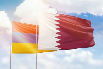 Sunny blue sky and flags of qatar and armenia