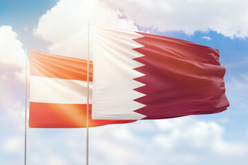 Sunny blue sky and flags of qatar and austria
