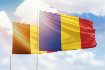 Sunny blue sky and flags of romania and belgium