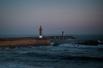 Fototapeta premium A pier with a lighthouse in the overcast evening ocean.