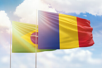 Sunny blue sky and flags of romania and brazil
