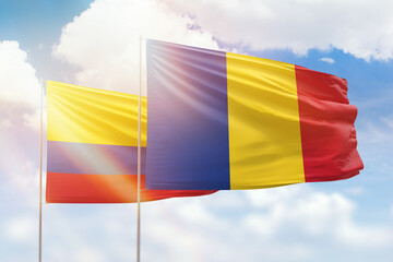 Sunny blue sky and flags of romania and colombia