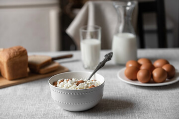 At home, in the kitchen, the table is covered with a linen tablecloth and there are natural and healthy products, milk and cottage cheese, bread and boiled chicken eggs on it