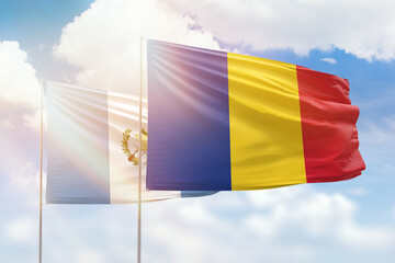 Sunny blue sky and flags of romania and guatemala