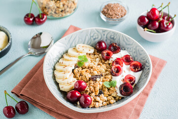 Granola with cherry, banana and flax seeds in a bowl on the table. Homemade breakfast. Close-up