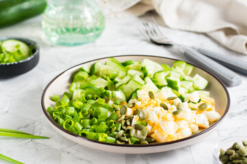 Fresh salad of cucumber, boiled egg and green onion on a plate on the table. Ketogenic diet.