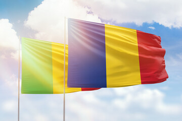 Sunny blue sky and flags of romania and mali