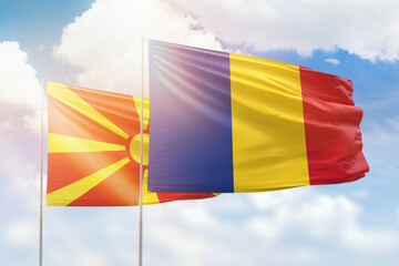Sunny blue sky and flags of romania and north macedonia