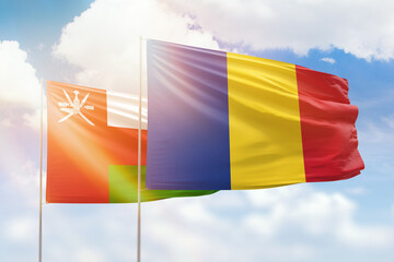 Sunny blue sky and flags of romania and oman