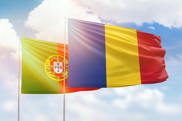 Sunny blue sky and flags of romania and portugal