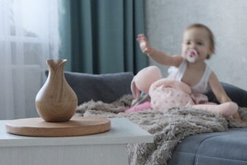 Aromatherapy concept. Little cheerful european girl with blond hair at home with a diffuser. Wooden...