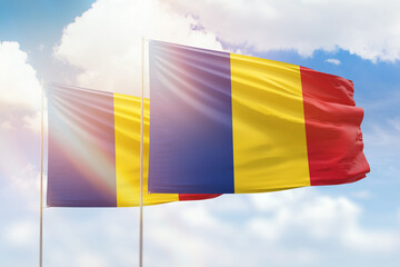 Sunny blue sky and flags of romania and romania