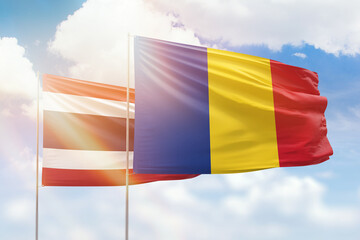 Sunny blue sky and flags of romania and thailand