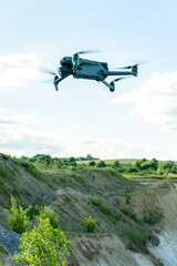 Fototapeta na wymiar The drone hovered against the background of clouds over a beautiful landscape. The use of a modern drone to search for minerals and explore the territory of the quarry.