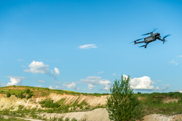 Fototapeta na wymiar The drone hovered against the background of clouds over a beautiful landscape. The use of a modern drone to search for minerals and explore the territory of the quarry.