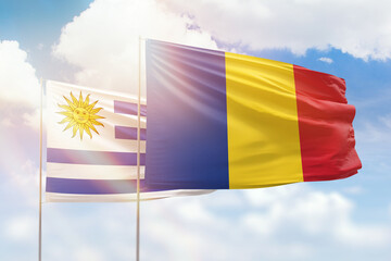 Sunny blue sky and flags of romania and uruguay