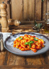 Italian Gnocchi with tomato sauce and basil on wooden background