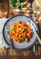 Traditional Italian potato Gnocchi with tomato sauce and fresh basil with glas of white wine. rustic background