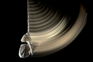 The stone is swinging on a rope.Motion blur.