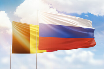 Sunny blue sky and flags of russia and belgium