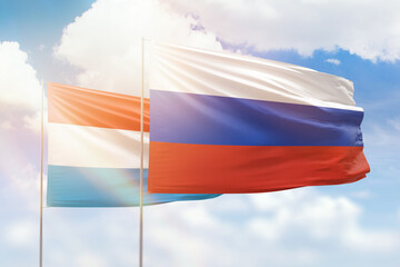 Sunny blue sky and flags of russia and luxembourg