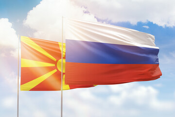 Sunny blue sky and flags of russia and north macedonia