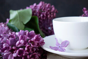 white cup and a bouquet of lilacs on the table