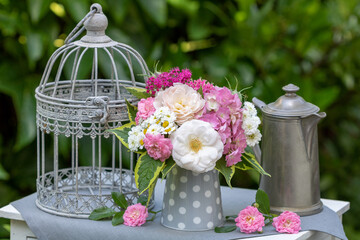 Dekoration mit Blumenstrauß mit Sommerblumen und vintage Kaffeekanne und Vogelkäfig