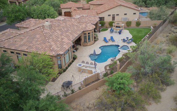 An Ariel view of a desert landscaped home in Arizona featuring a travertine tiled pool deck and outdoor fireplace.