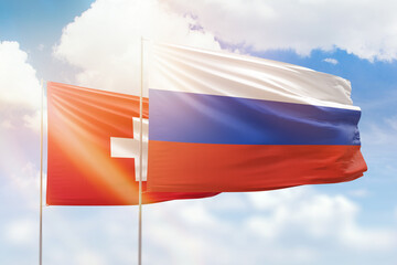 Sunny blue sky and flags of russia and switzerland