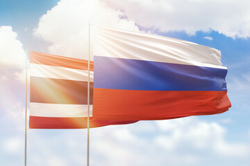 Sunny blue sky and flags of russia and thailand