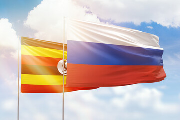 Sunny blue sky and flags of russia and uganda