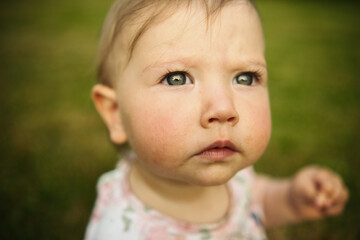 child sitting on the grass and looking at the camera