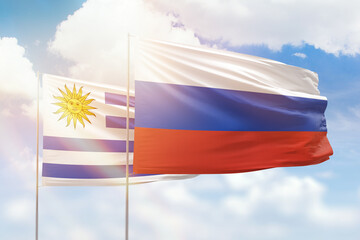 Sunny blue sky and flags of russia and uruguay