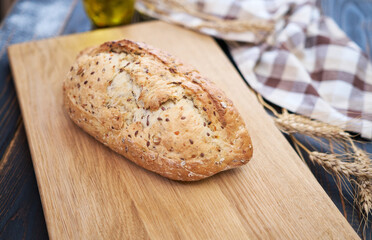 Fresh bread loaf on wooden cutting board at kitchen table