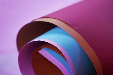Colorful manila paper rolls background in pink, red, blue and orange colors. Sheets of paper in variety colors.