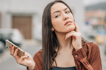 girl with mobile phone and distrustful expression - obrazy, fototapety, plakaty