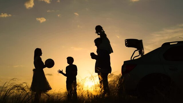 Dad with child, daughter, mother, children play with ball against backdrop of beautiful sunset next to car, Travelling by car. Happy family travels by car. Parents, children stopped at campsite by car